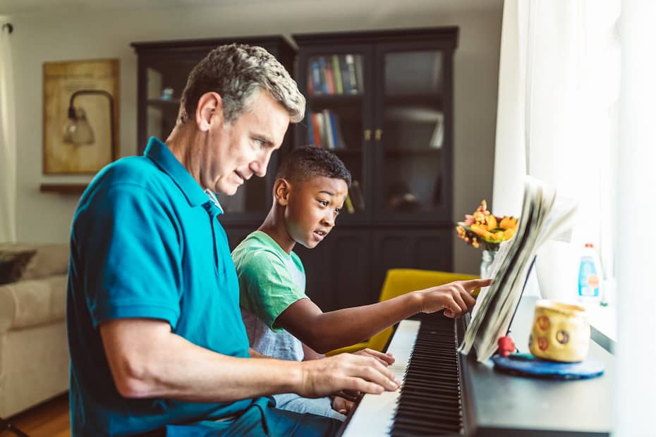 a man in blue polo shirt playing piano beside a boy